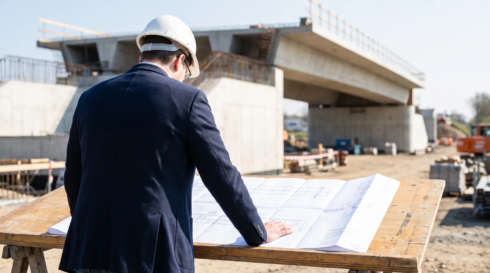 Bauingenieur bei der technischen Planprüfung vor einem Ingenieurbauwerk