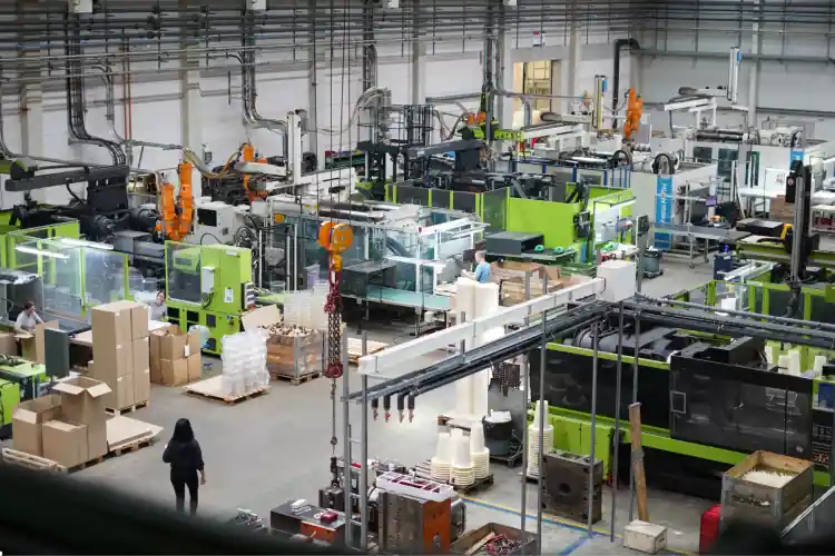 Produktionshalle im deutschen Mittelstand mit Maschinen, Förderband und Fachkräften im Schichtbetrieb