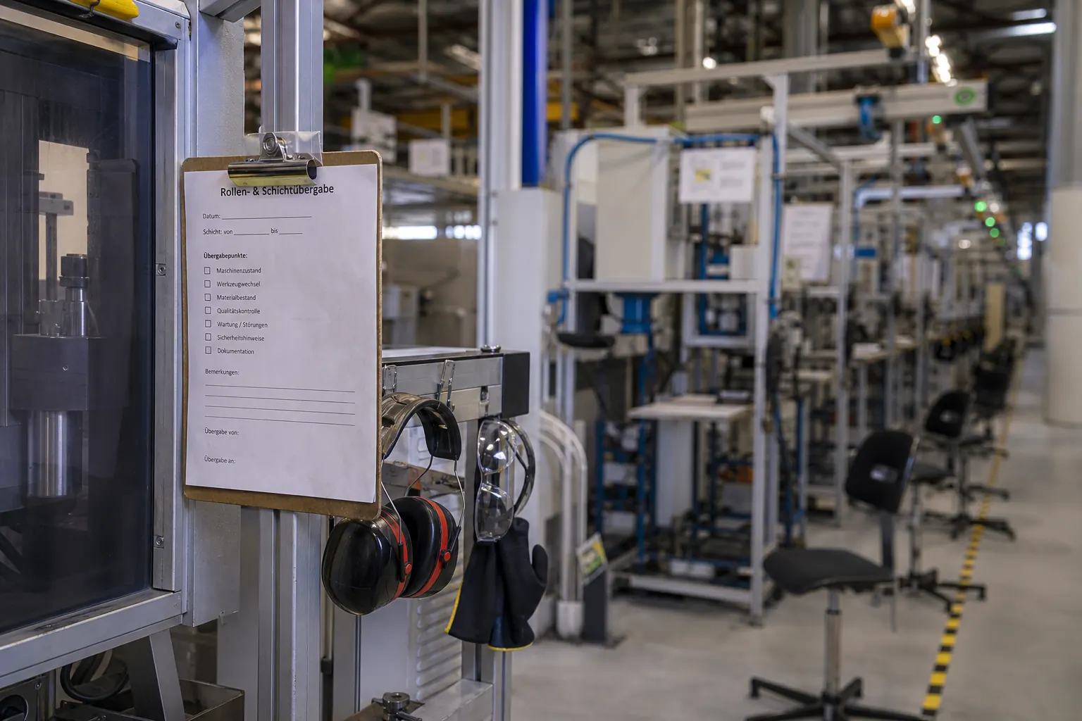 Leere Arbeitsplätze an einer Produktionslinie mit Checkliste am Maschinenplatz als Symbol für Abgänge in der Schicht