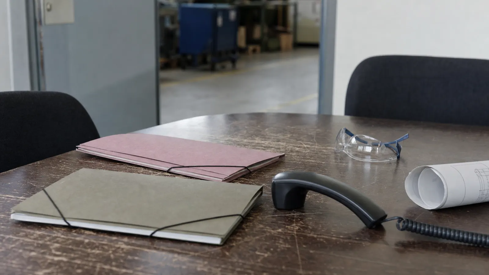 Geschlossene Personalmappen und ein Telefon auf einem Besprechungstisch in einem Industrieunternehmen